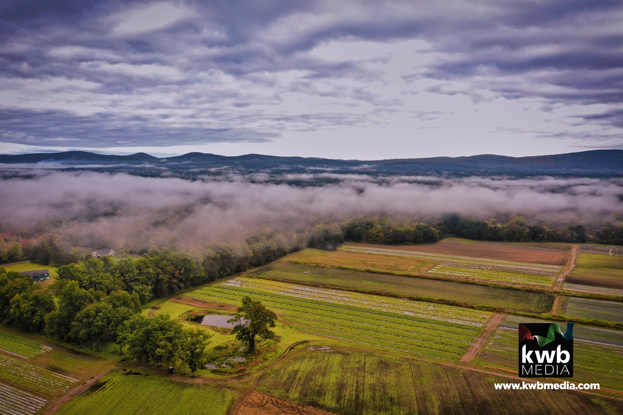 Drone aerial of Connecticut farm fields under morning fog